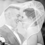 A man and woman under the veil of their wedding day.