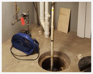 A hole in the floor with pipes and a hose connected to it.